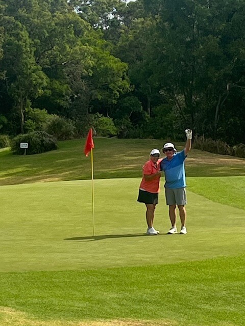 John Tetley posing with a golf ball next to the hole he scored a hole in one